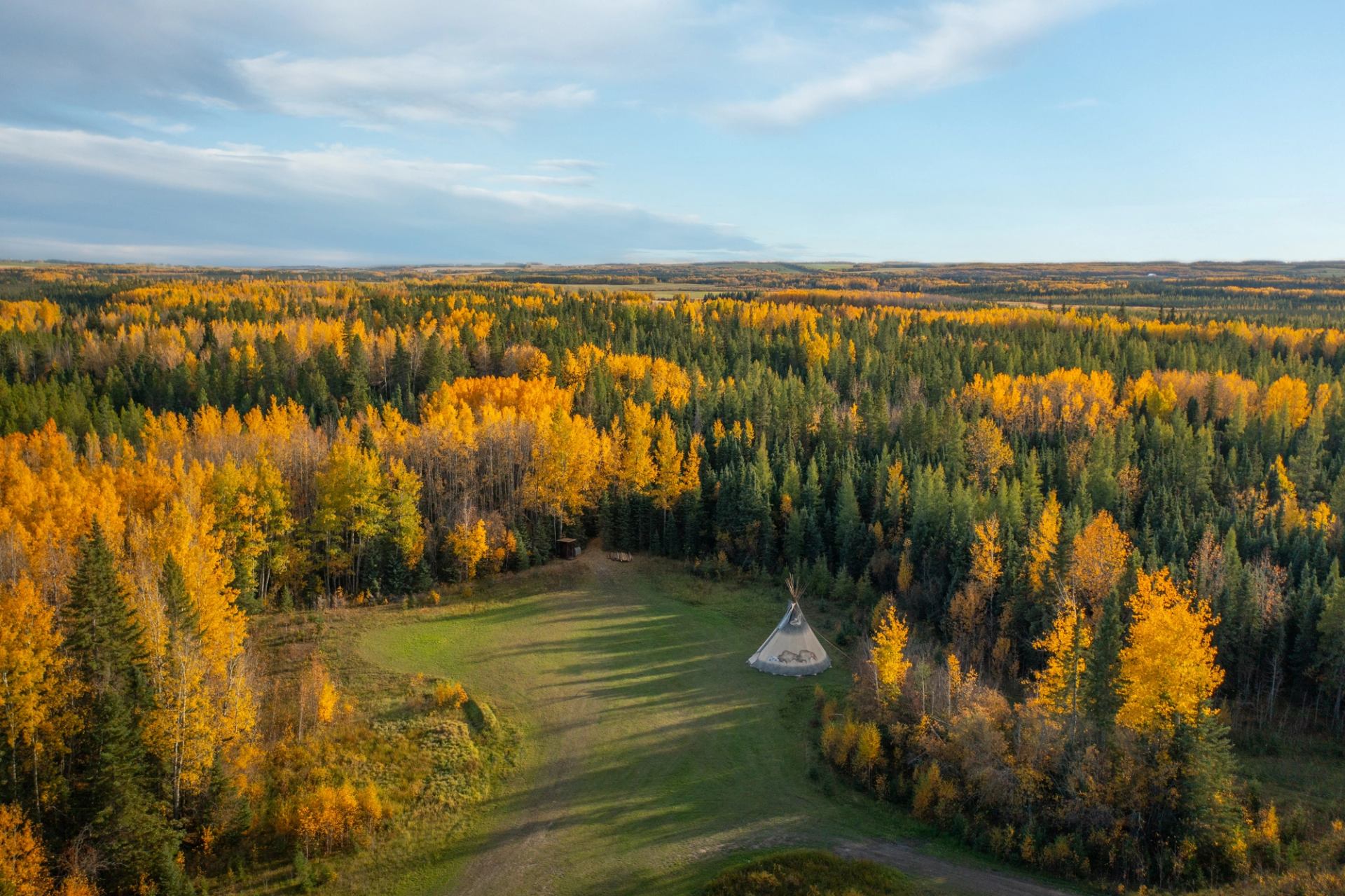 Overhead view of a tipi in a clearing surrounded by forest.