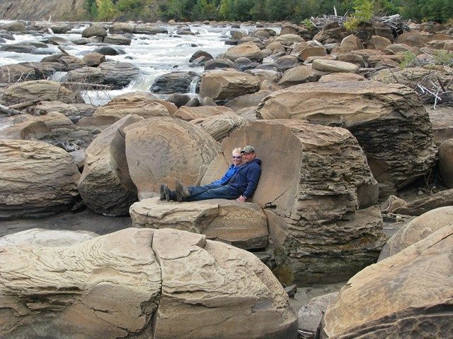 Couple relaxing on a large Concretion at the Grand Rapids (Athabasca River) Alberta.