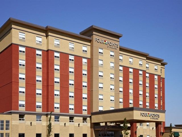 Exterior of Four Points By Sheraton with red-beige panels and clear blue sky.