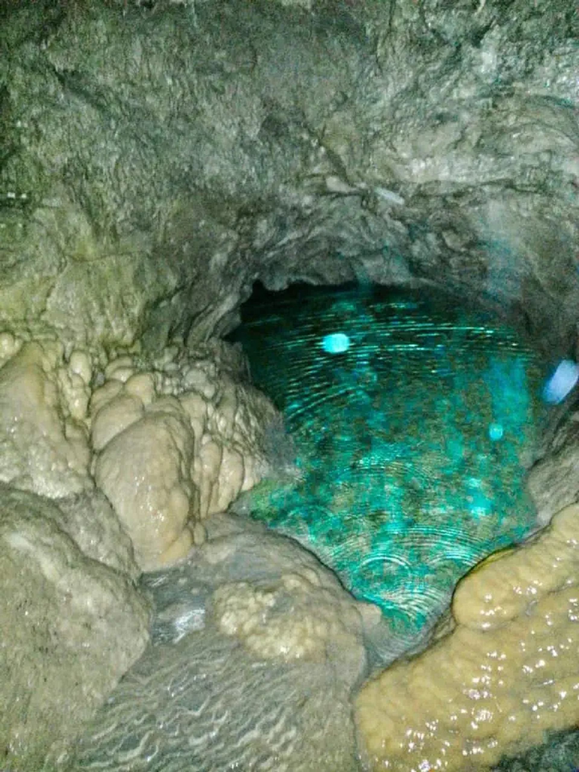A clear turquoise pool surrounded by smooth limestone formations inside Rat’s Nest Cave.