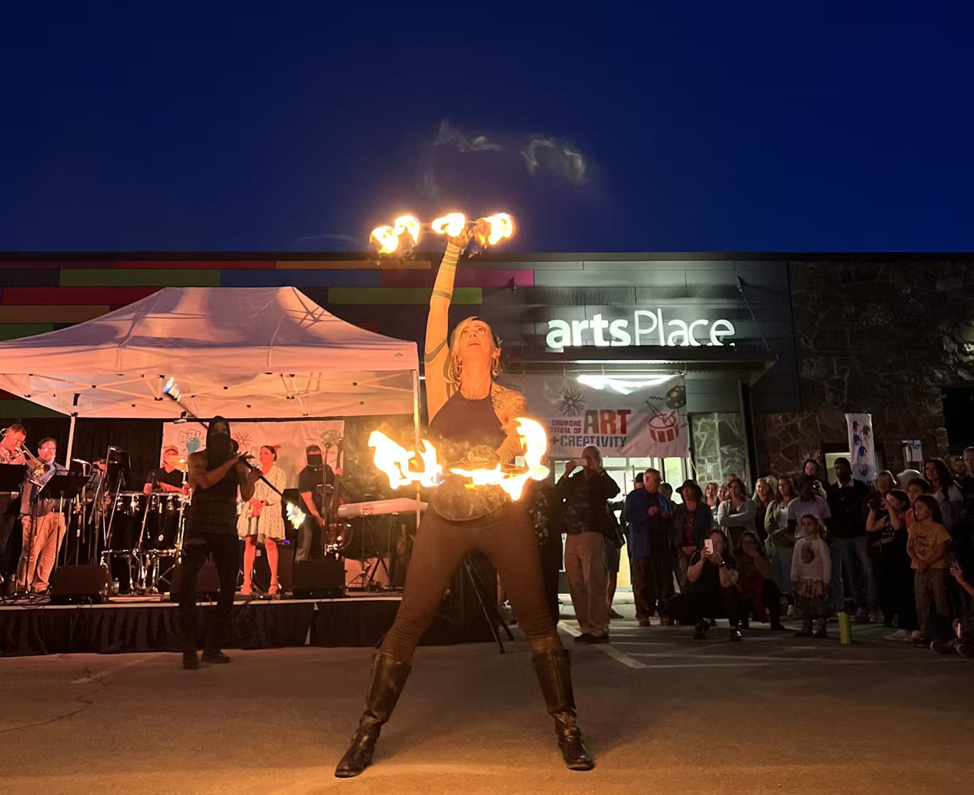 Fire performer entertains crowd at night outside artsPlace during a live event.