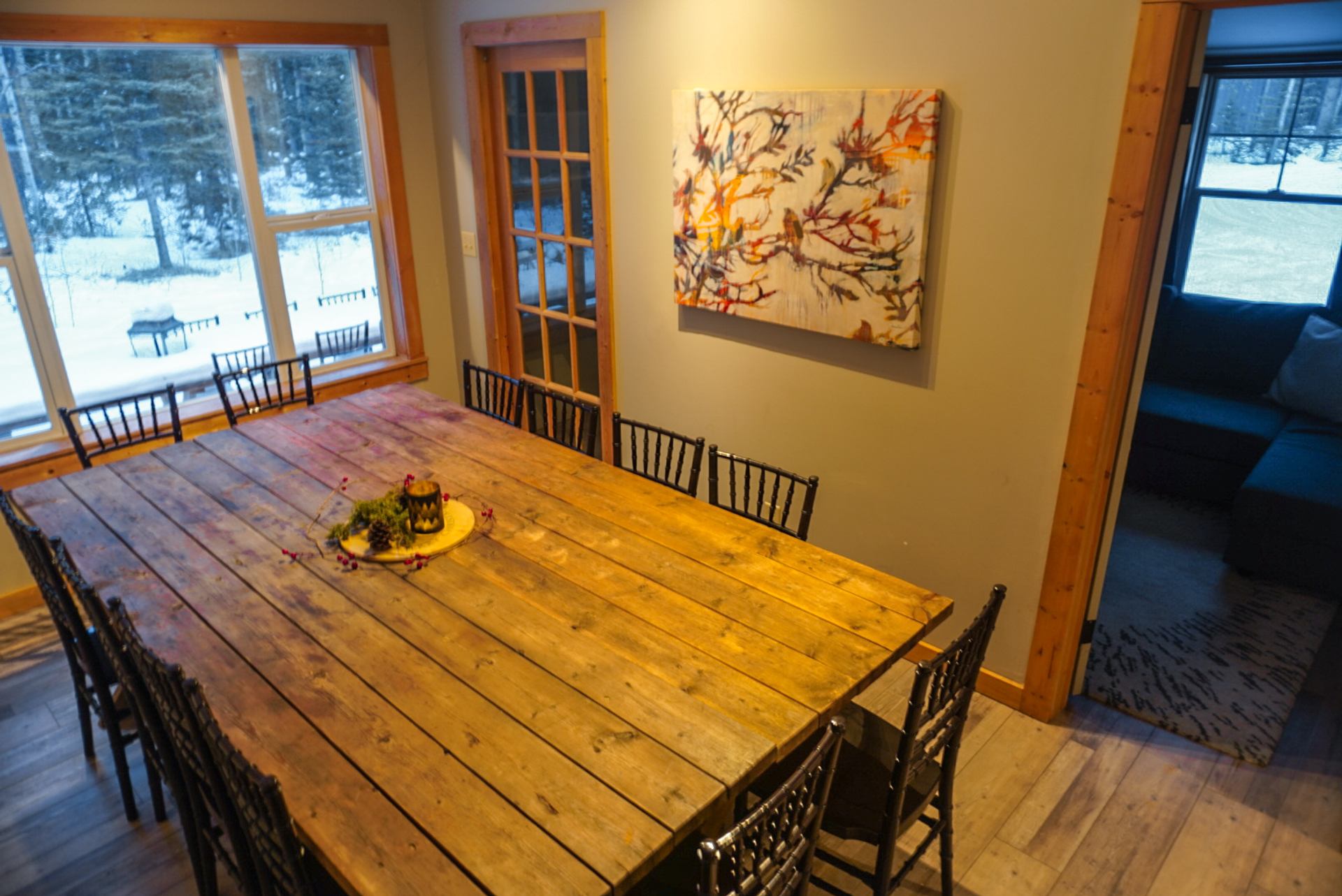 Rustic wooden dining table with chairs near large windows at Trembling Aspen Retreat.
