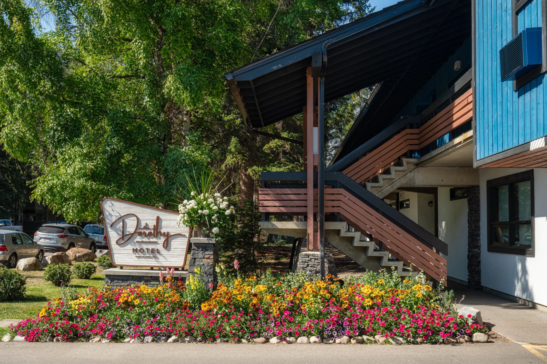 Teal building with stairs in front, garden beds and a sign saying The Dorothy Motel.