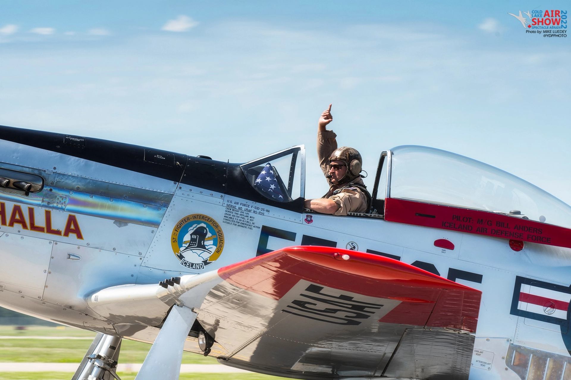A pilot waving from inside the aircraft.