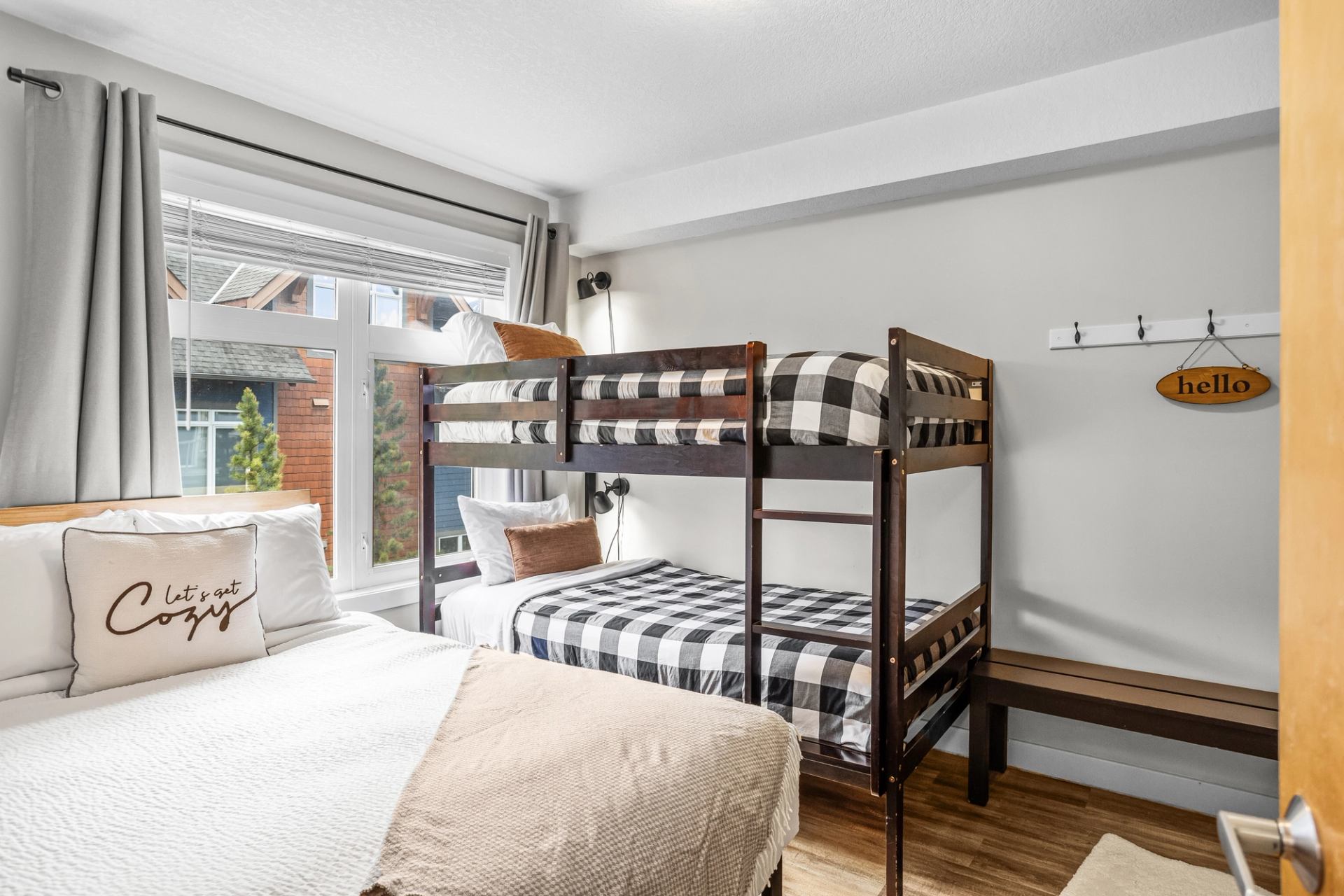 Bedroom with a double bed, wooden bunk beds, large window and bench.