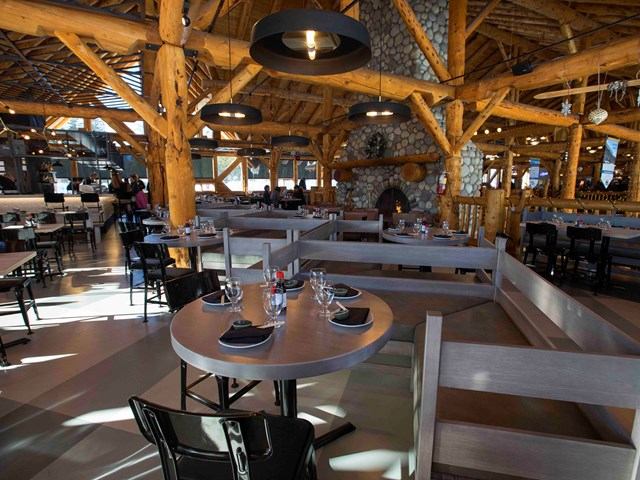 Rustic dining area with wooden beams, stone accents, and neatly set tables at Kuma Yama.