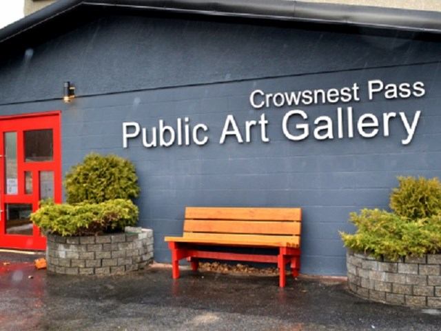 Crowsnest Pass Public Grt gallery building with a red bench outside.