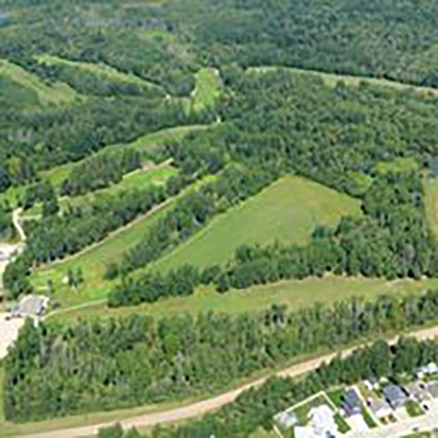 Aerial view of Silver Birch Golf Club surrounded by forest and rolling hills.
