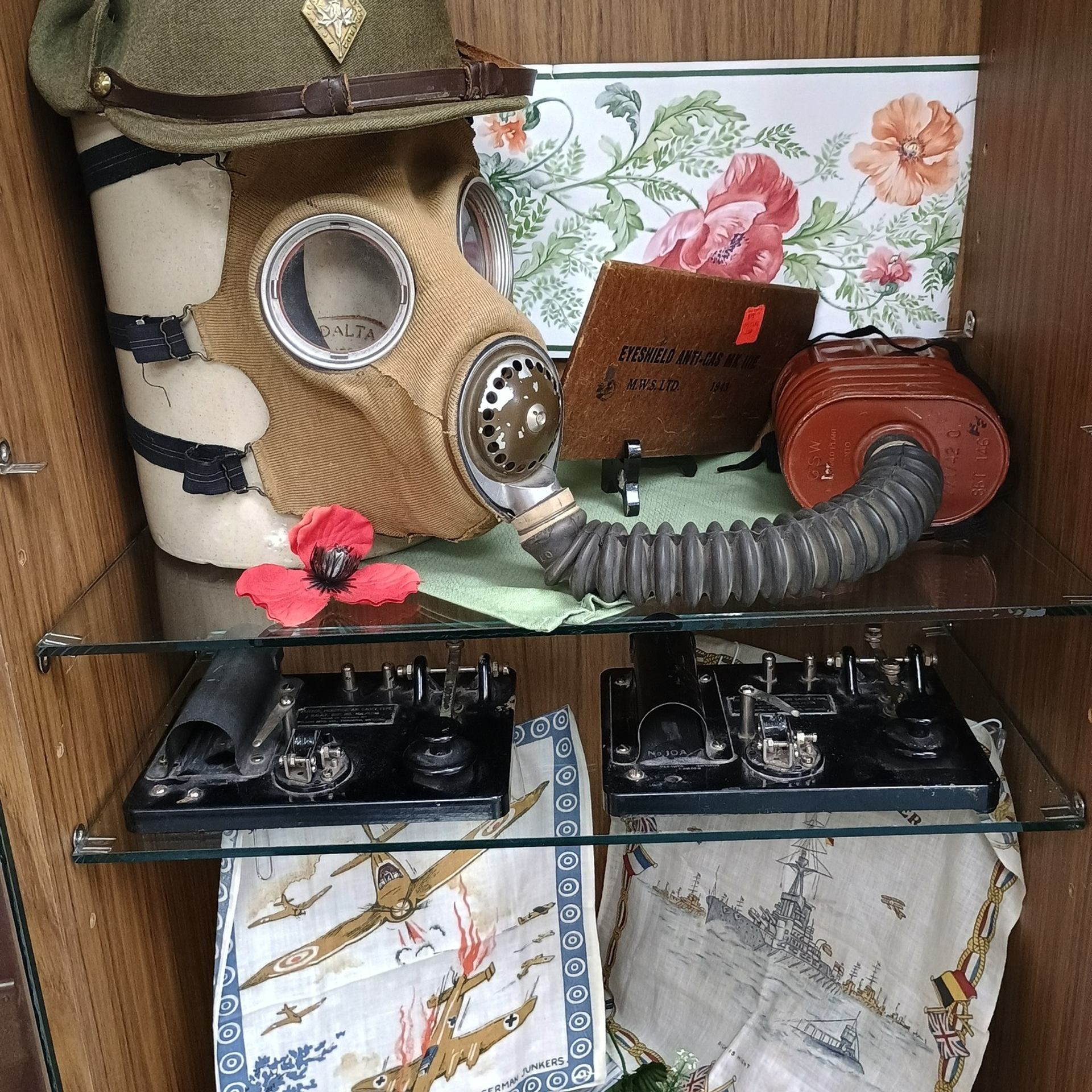 Vintage gas mask with hose, military cap, and telegraph equipment on shelves