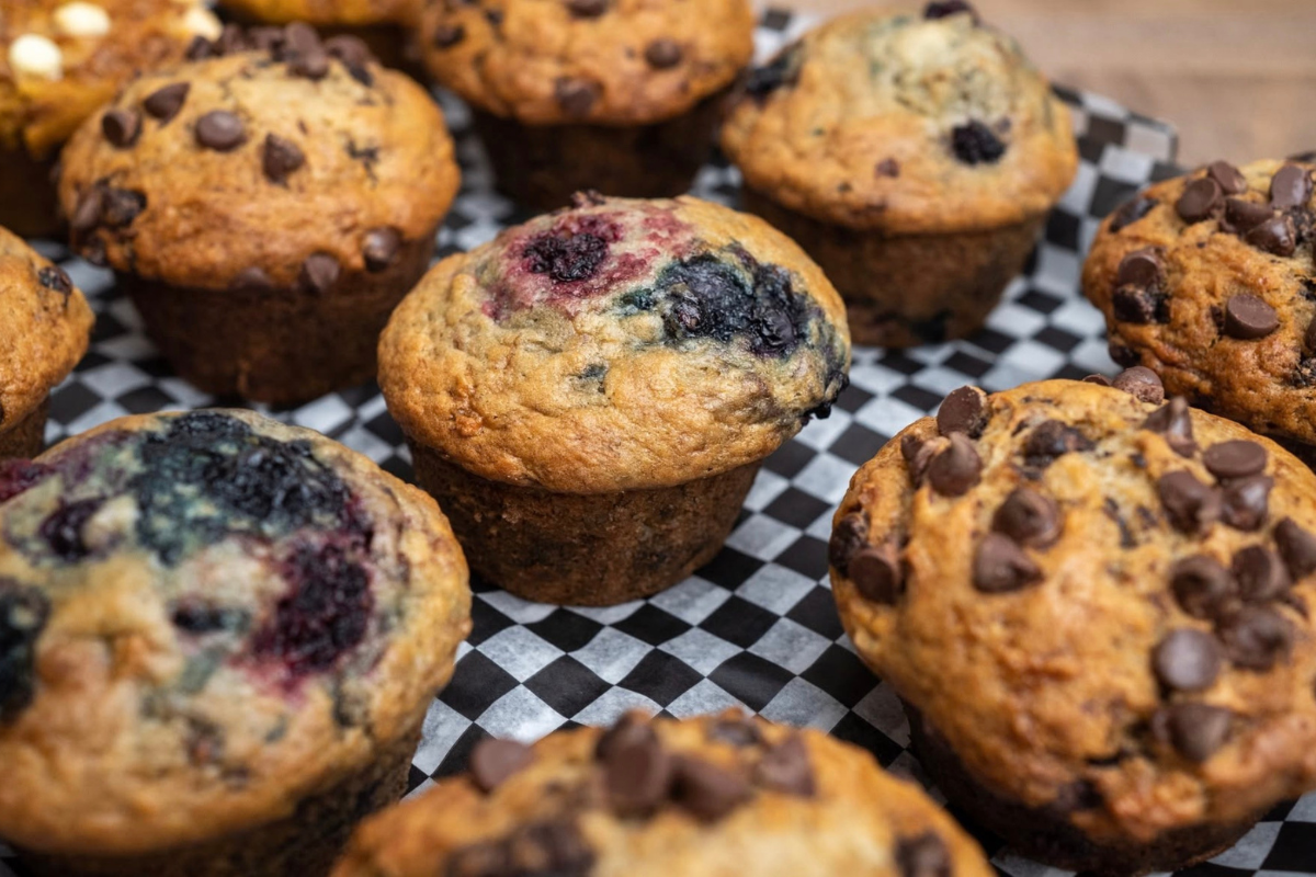 Blueberry and chocolate chip muffins arranged on black-and-white checkered paper.