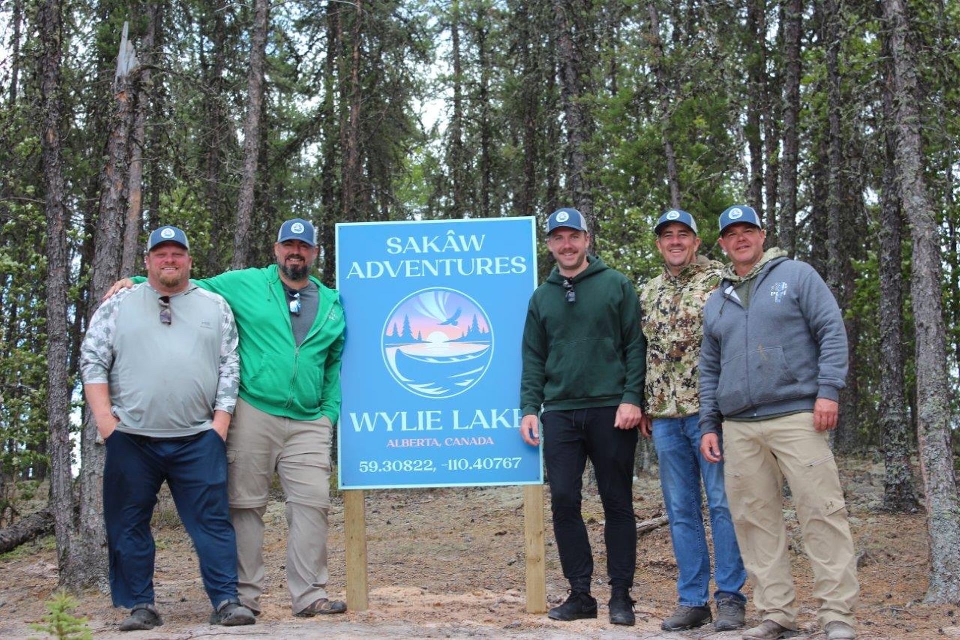 Group at Sakâw Adventures sign in forested campground.