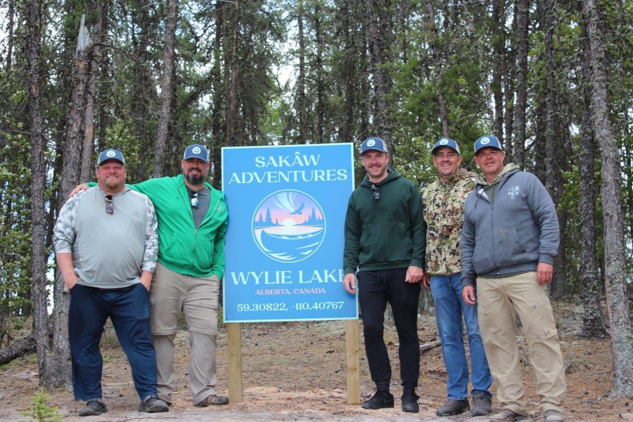 Group at Sakâw Adventures sign in forested campground.