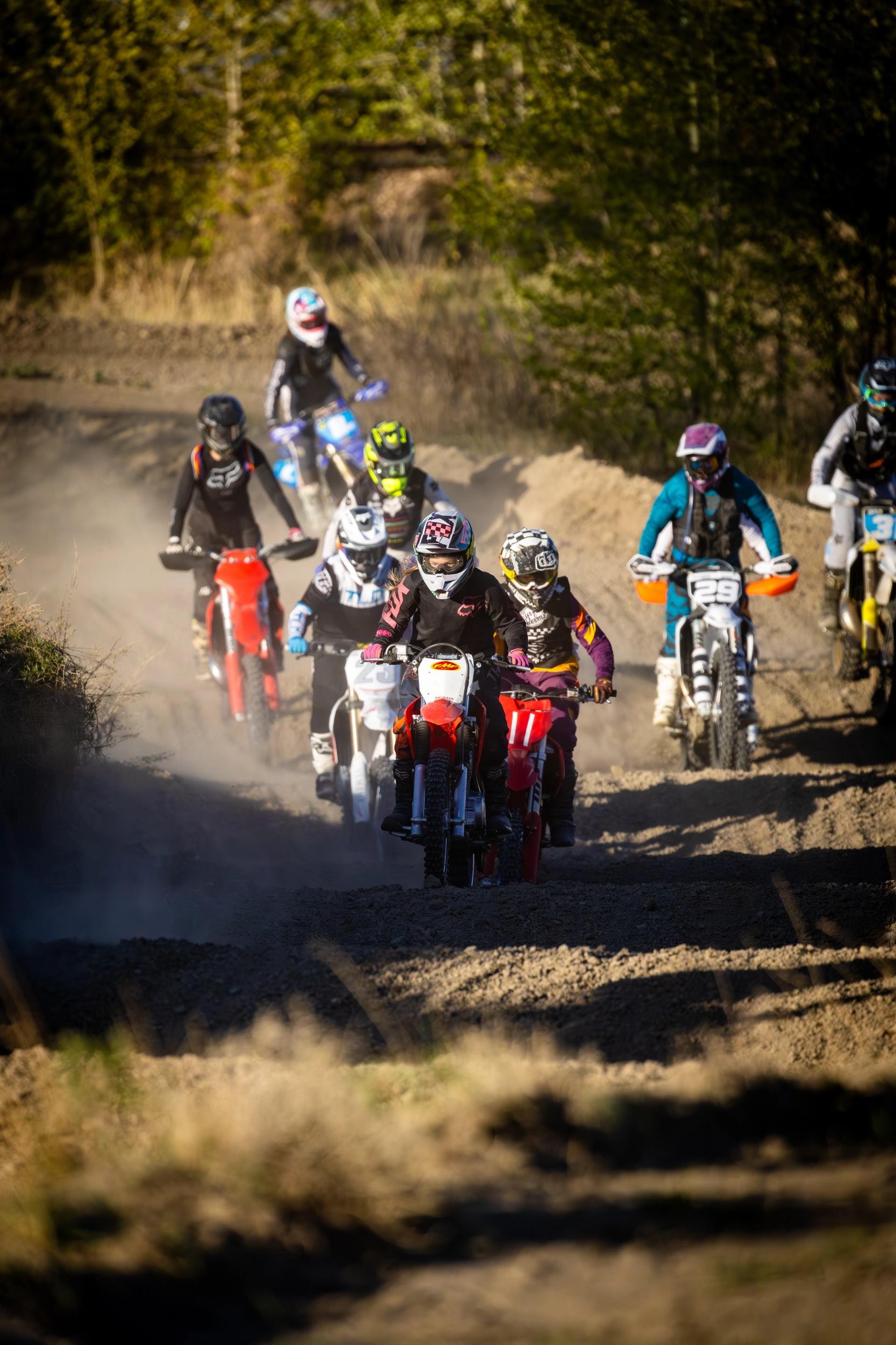 Motocross riders racing on a dusty dirt track in full gear.