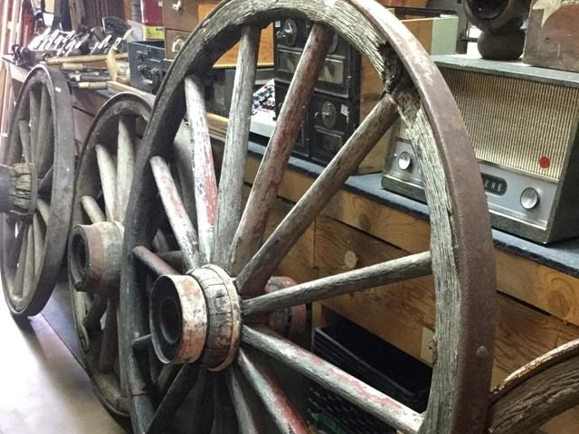 Antique wooden wagon wheels lean against a shelf of vintage radios.
