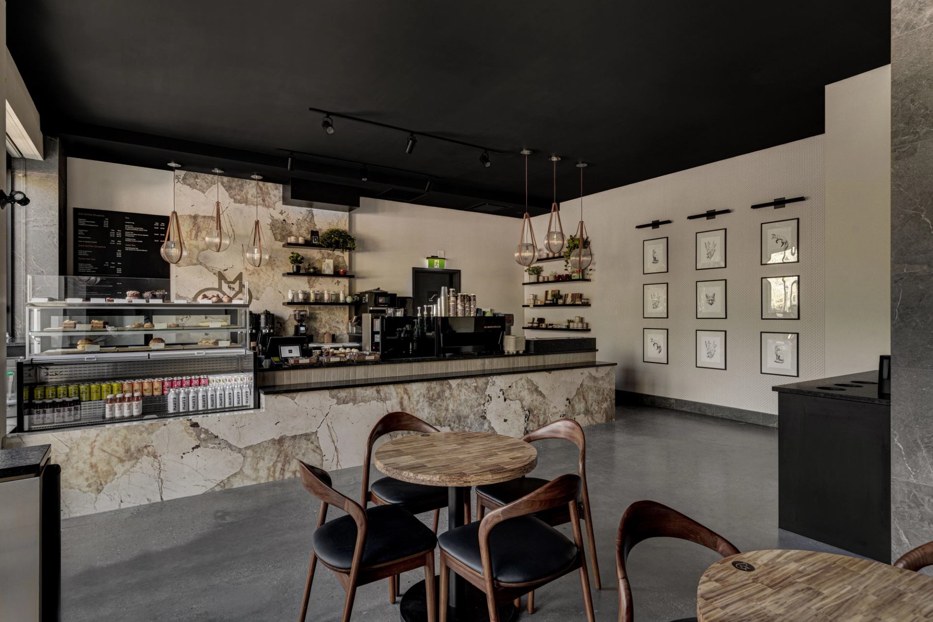 Café Foxtrot interior with marble counter, pastry case, coffee bar, and wood café seating.