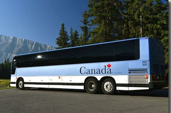Canada Coach Lines bus parked on road with mountains and trees behind.