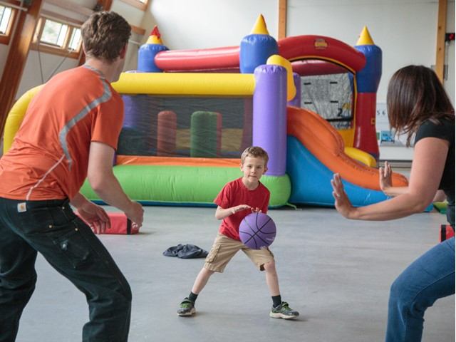 A family playing with a ball in front of a bouncy castle.