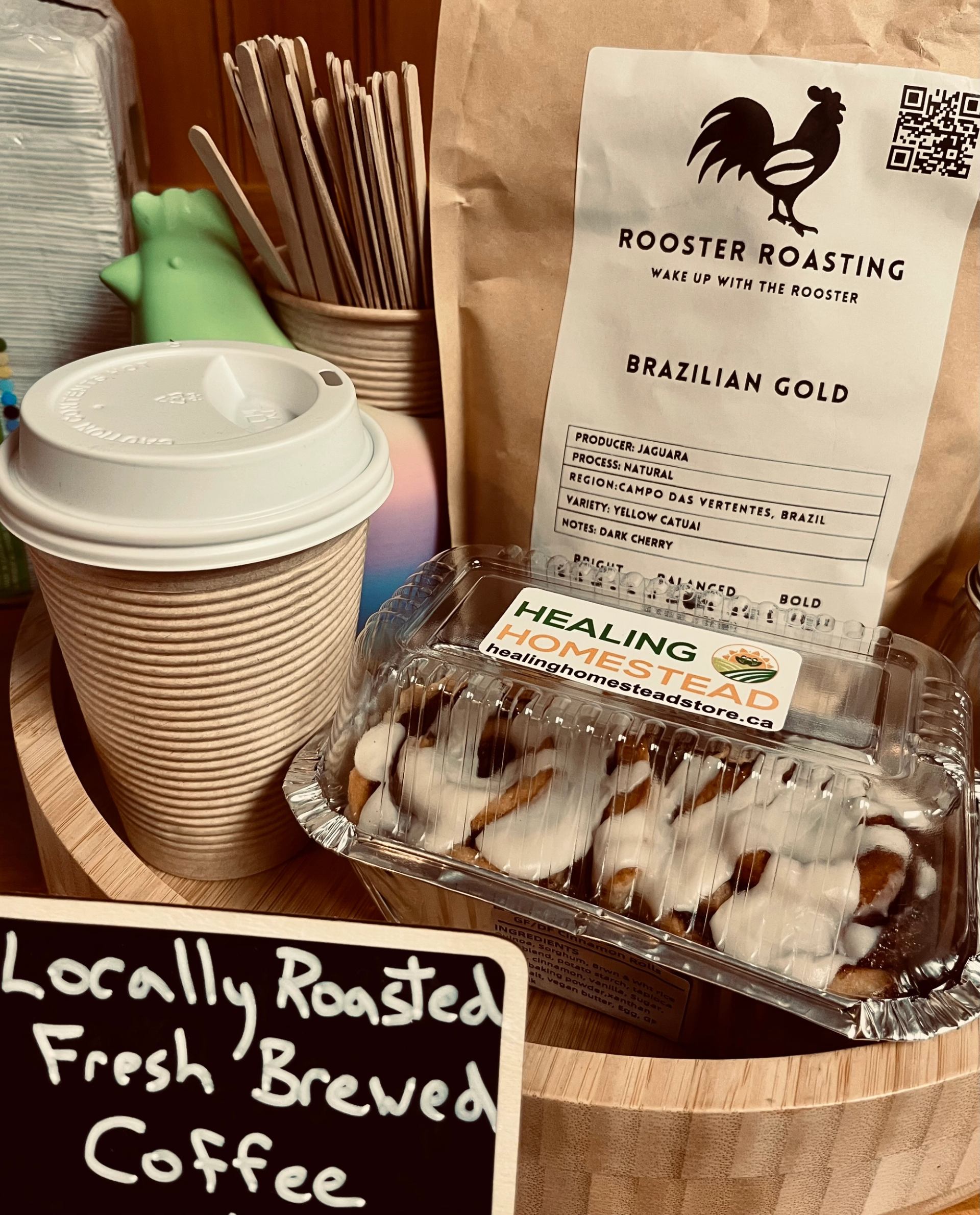Coffee cup, cinnamon rolls, and a bag of Brazilian roast beans on a wooden tray.