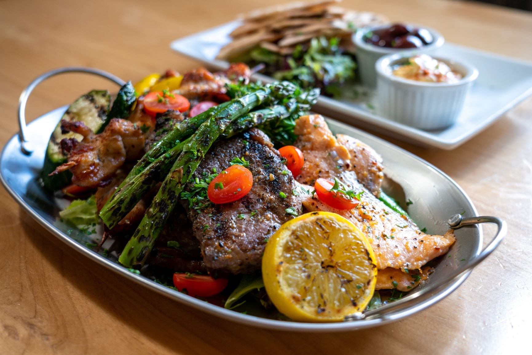 Grilled meats and veggies with pita, hummus, and greens at Alpha Bistro.