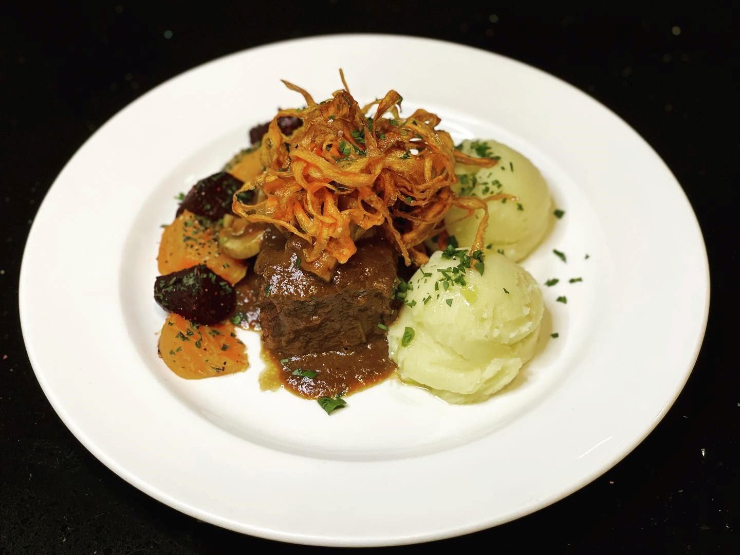Plated meal with mashed potatoes, roasted vegetables, and rich gravy on a white plate.