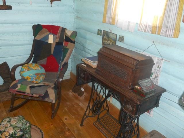 Antique sewing machine and patchwork chair in rustic museum room.