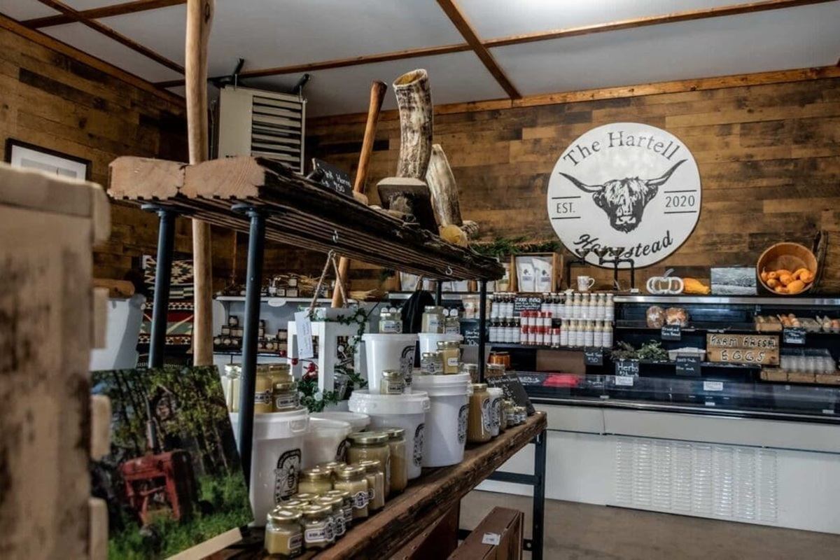 Farm shop interior with The Hartell Homestead sign, jars, buckets and produce displays.