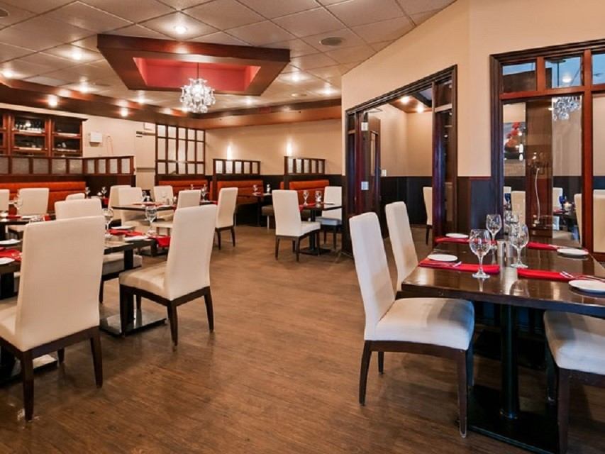 Hotel dining room with set tables, white chairs, and a chandelier overhead.