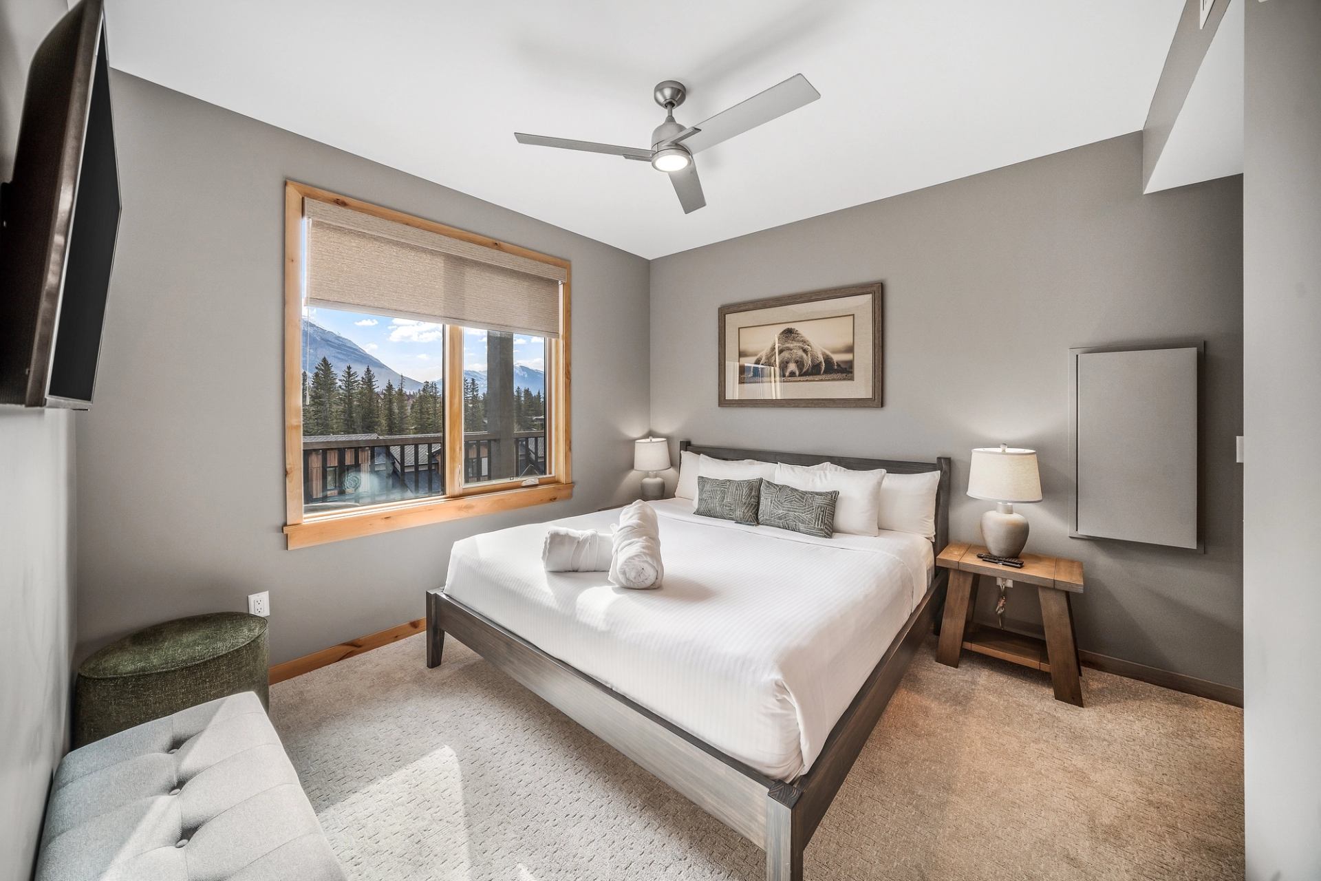 Bedroom with king bed, mountain view window, ceiling fan and bedside lamps.