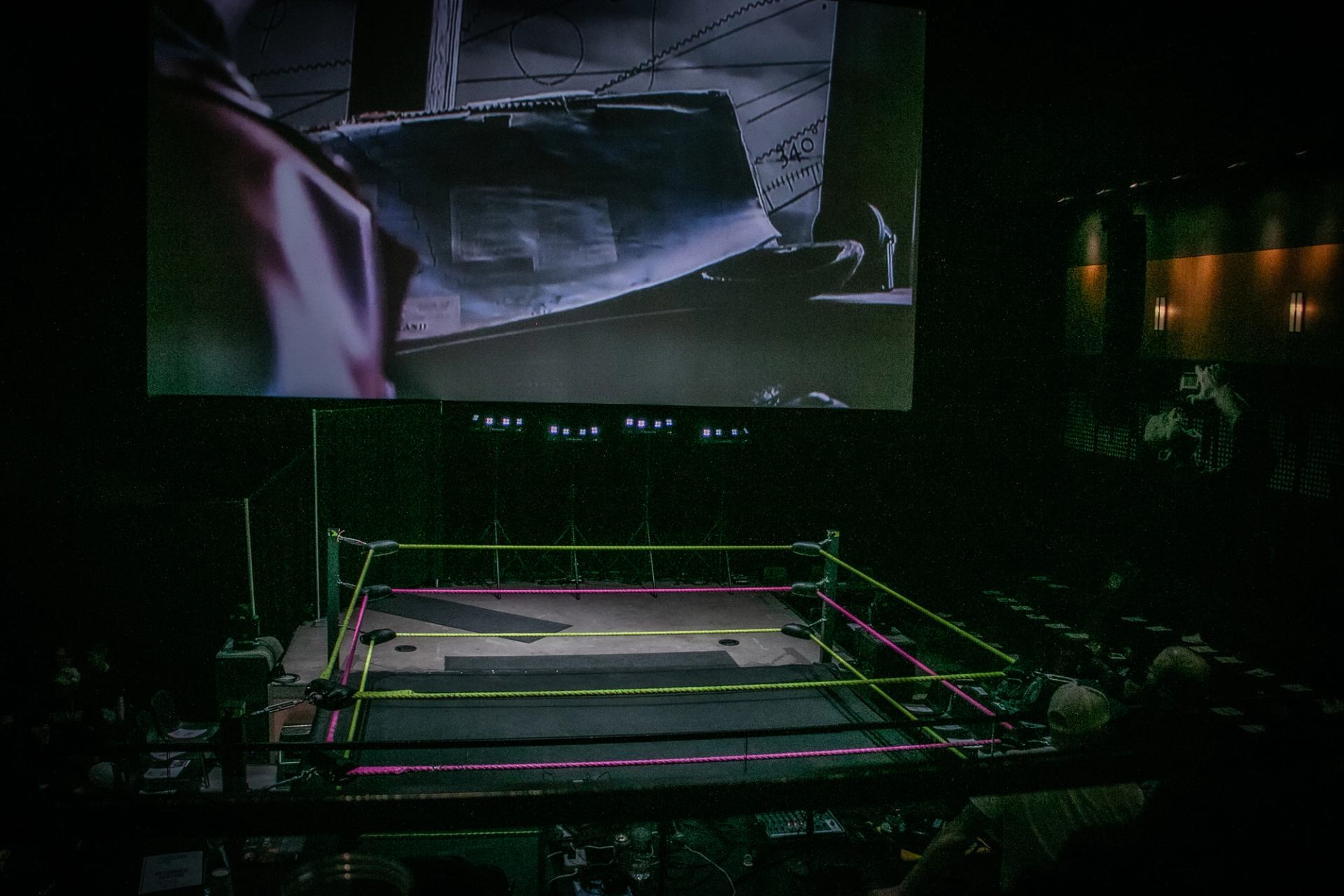 Empty wrestling ring under arena lights before a Love Pro Wrestling event with the crowd seated nearby.