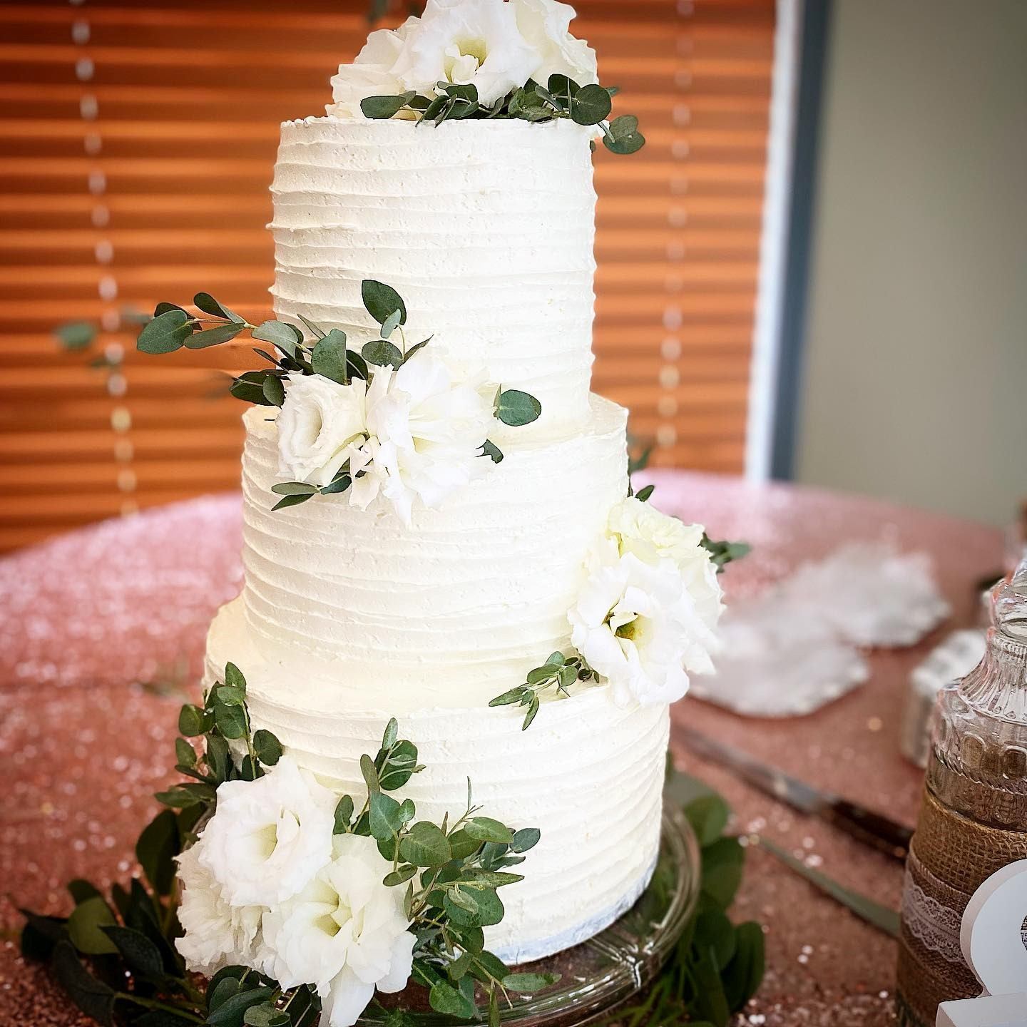 White tiered cake decorated with fresh white flowers and greenery