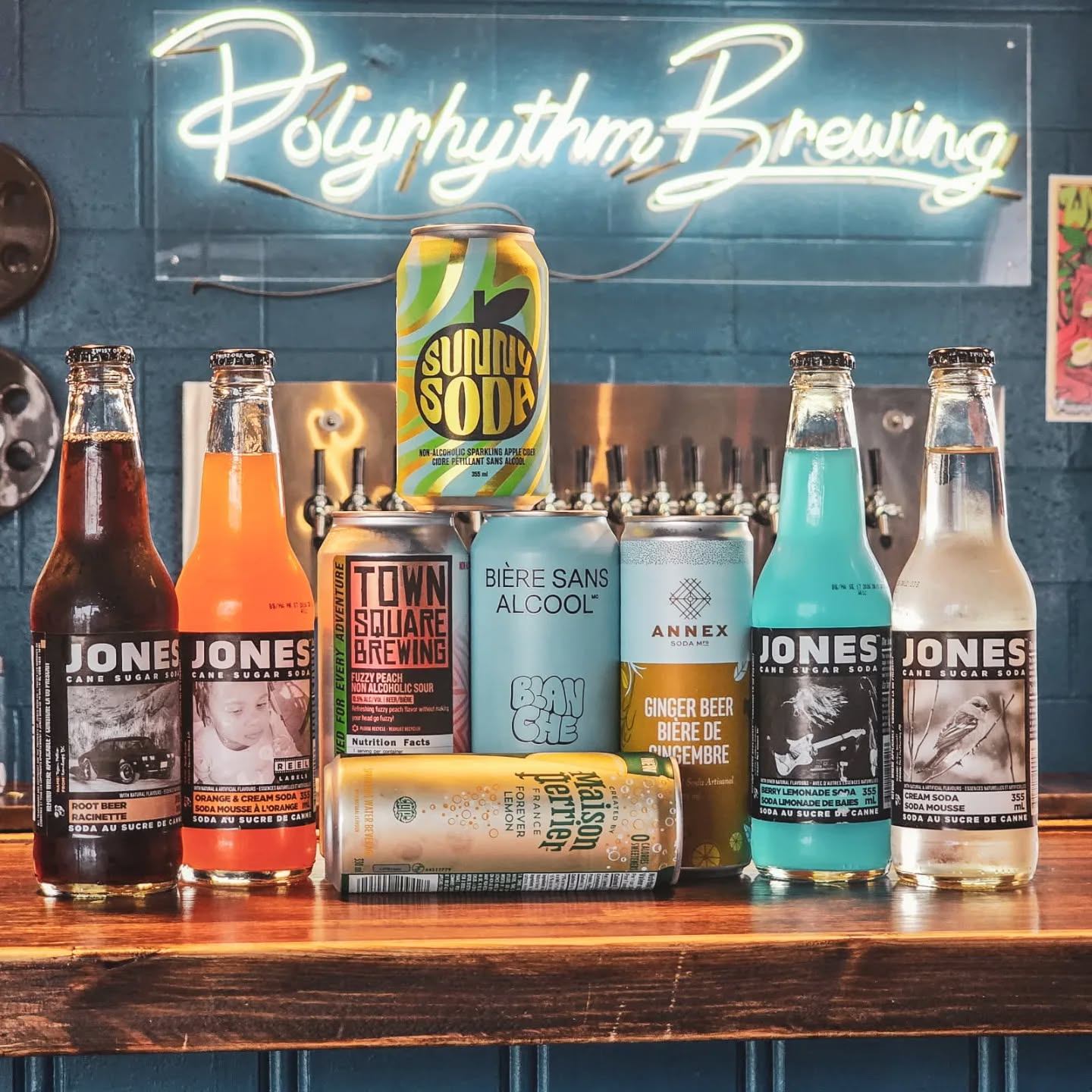 Assorted sodas and beers arranged on a bar with a Polyrhythm Brewing sign