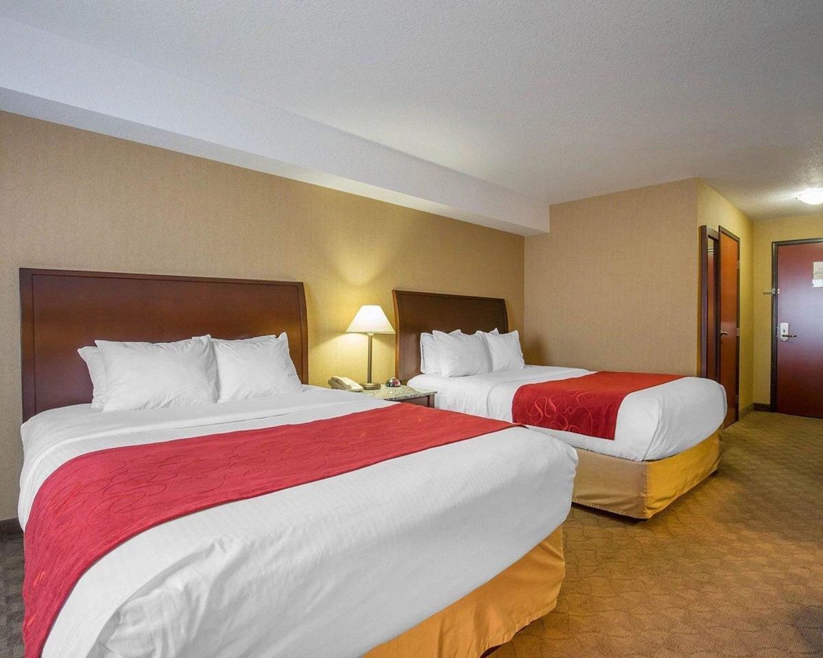 Guest room at Comfort Inn & Suites with two queen beds, red accents, and warm lighting.