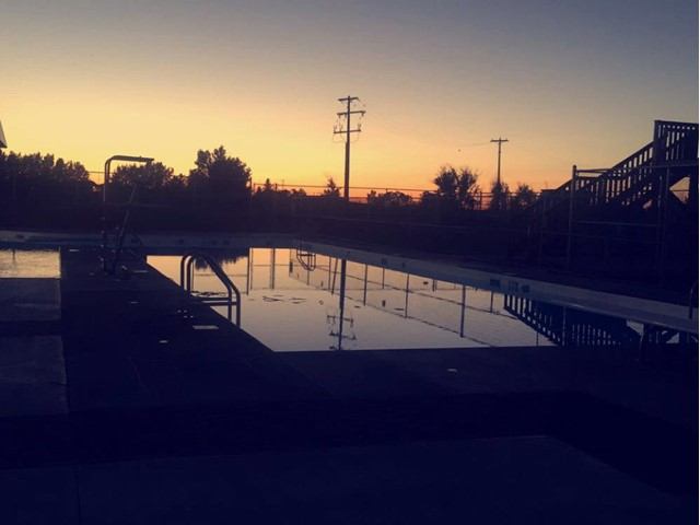Outdoor swimming pool reflecting a colorful sunset sky in Vauxhall.