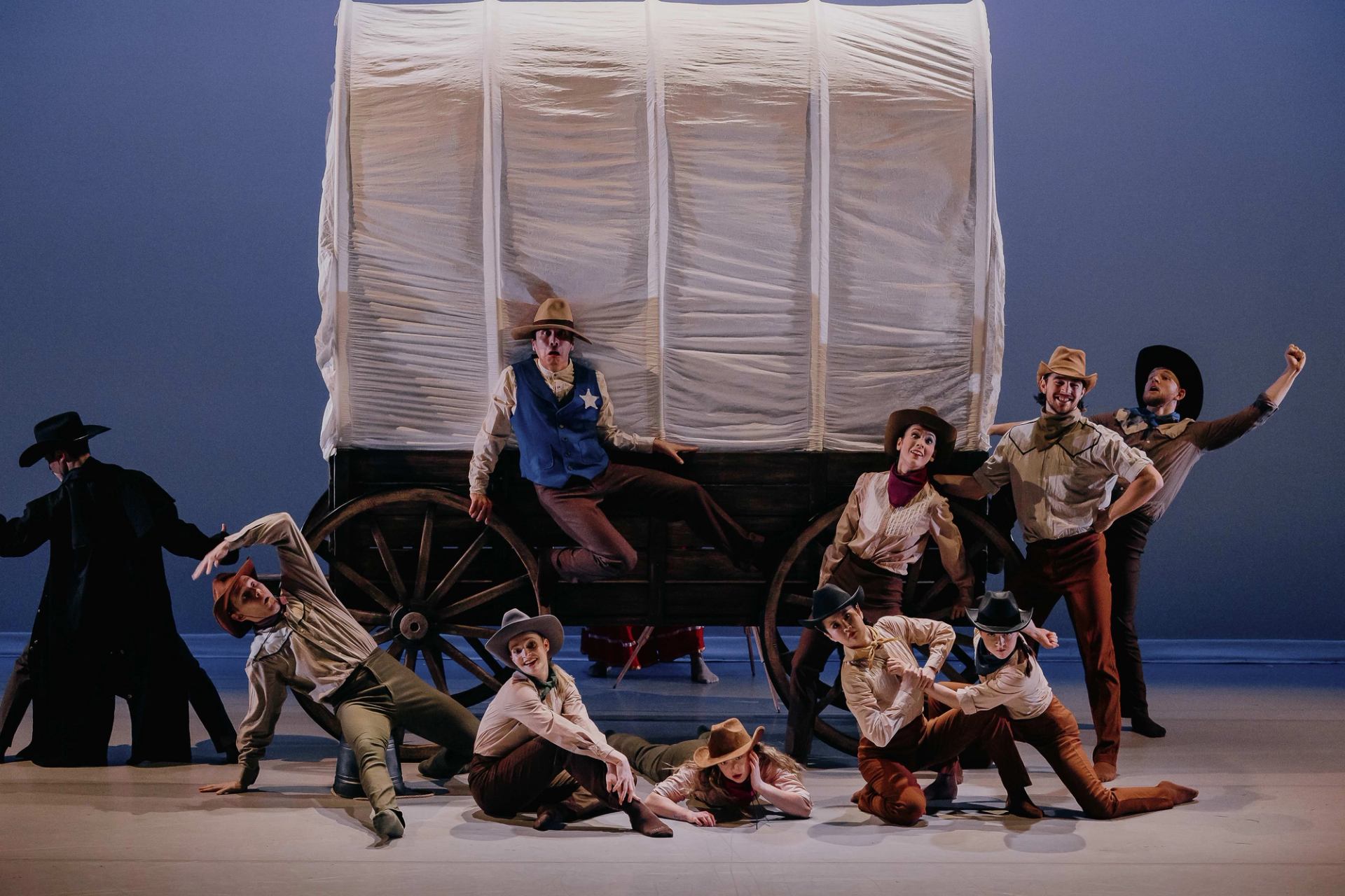 The performers of The Cowboy Act Suite & Other Works with a wagon behind them.