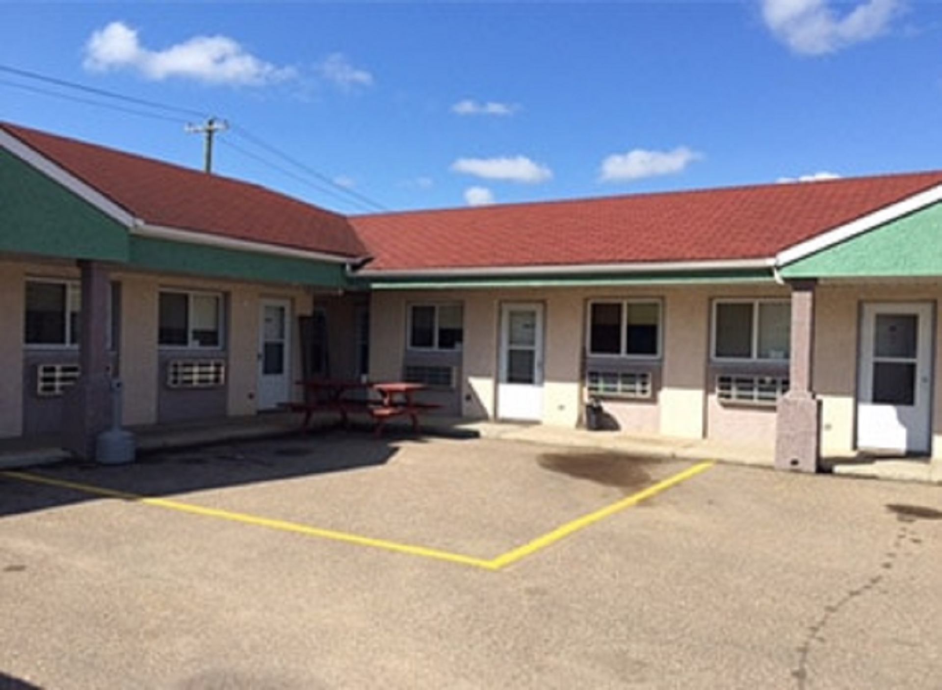 Exterior courtyard at Centre Suite Inns with motel‑style rooms, picnic table, and marked parking area.