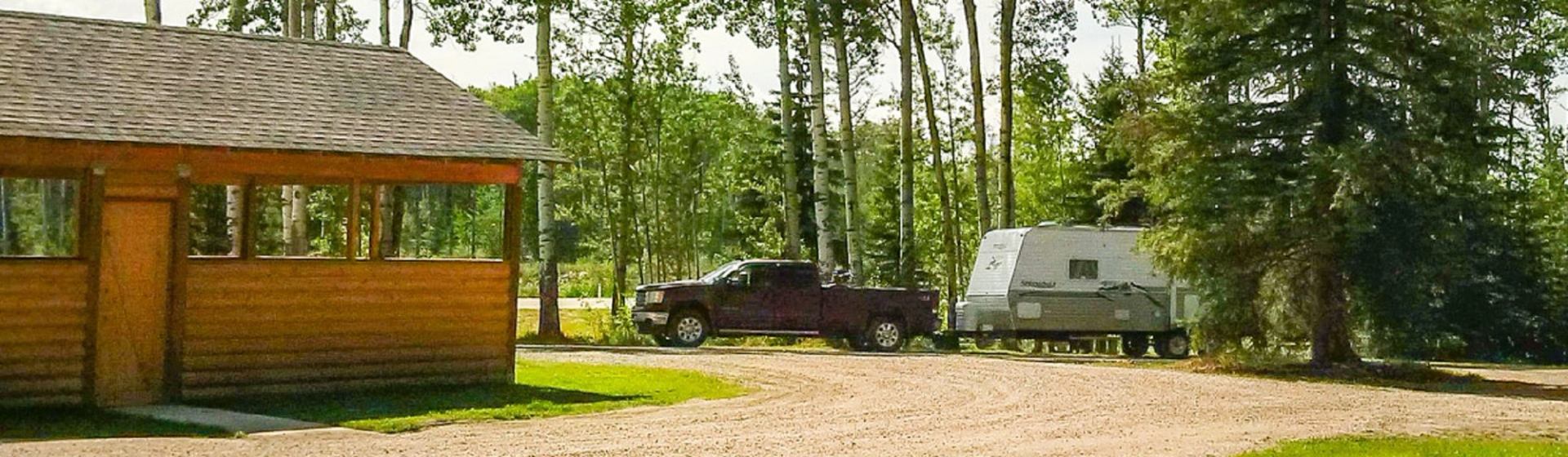Cabin and trailer in forested campground at Demmitt Provincial Recreation Area.