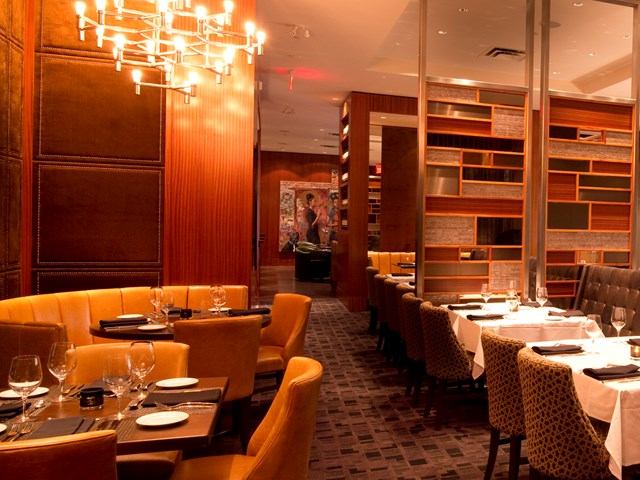Elegant dining room with yellow booths, patterned chairs, and modern chandelier.