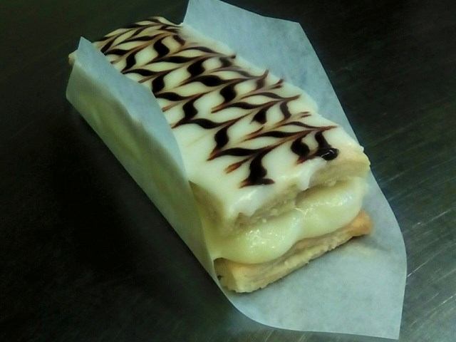 Layered gluten-free pastry with cream filling and chocolate-feathered icing.