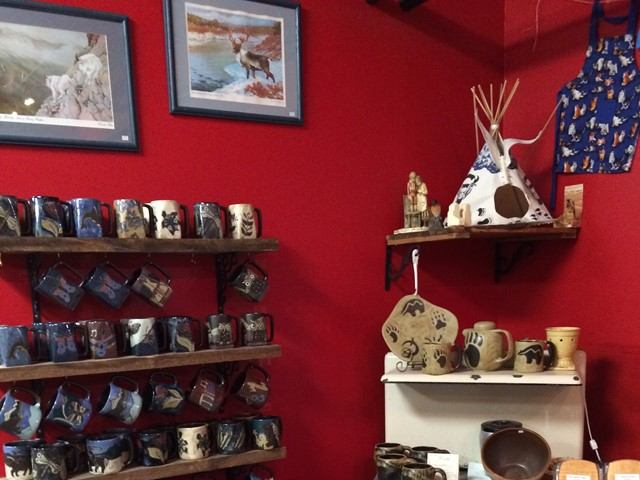 A room featuring a red wall adorned with shelves filled with various pottery pieces.