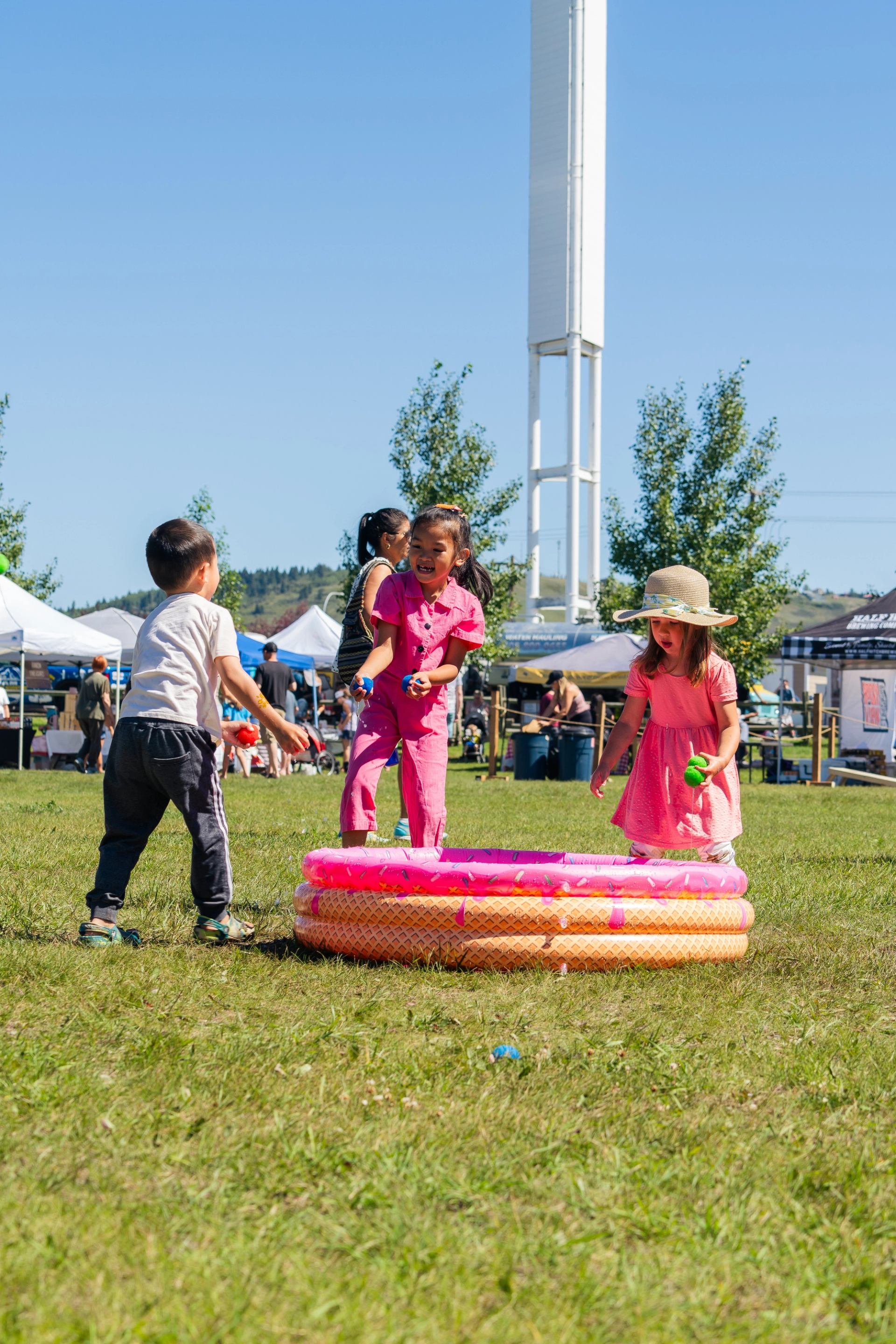 Children splashing in a small pink and orange pool.