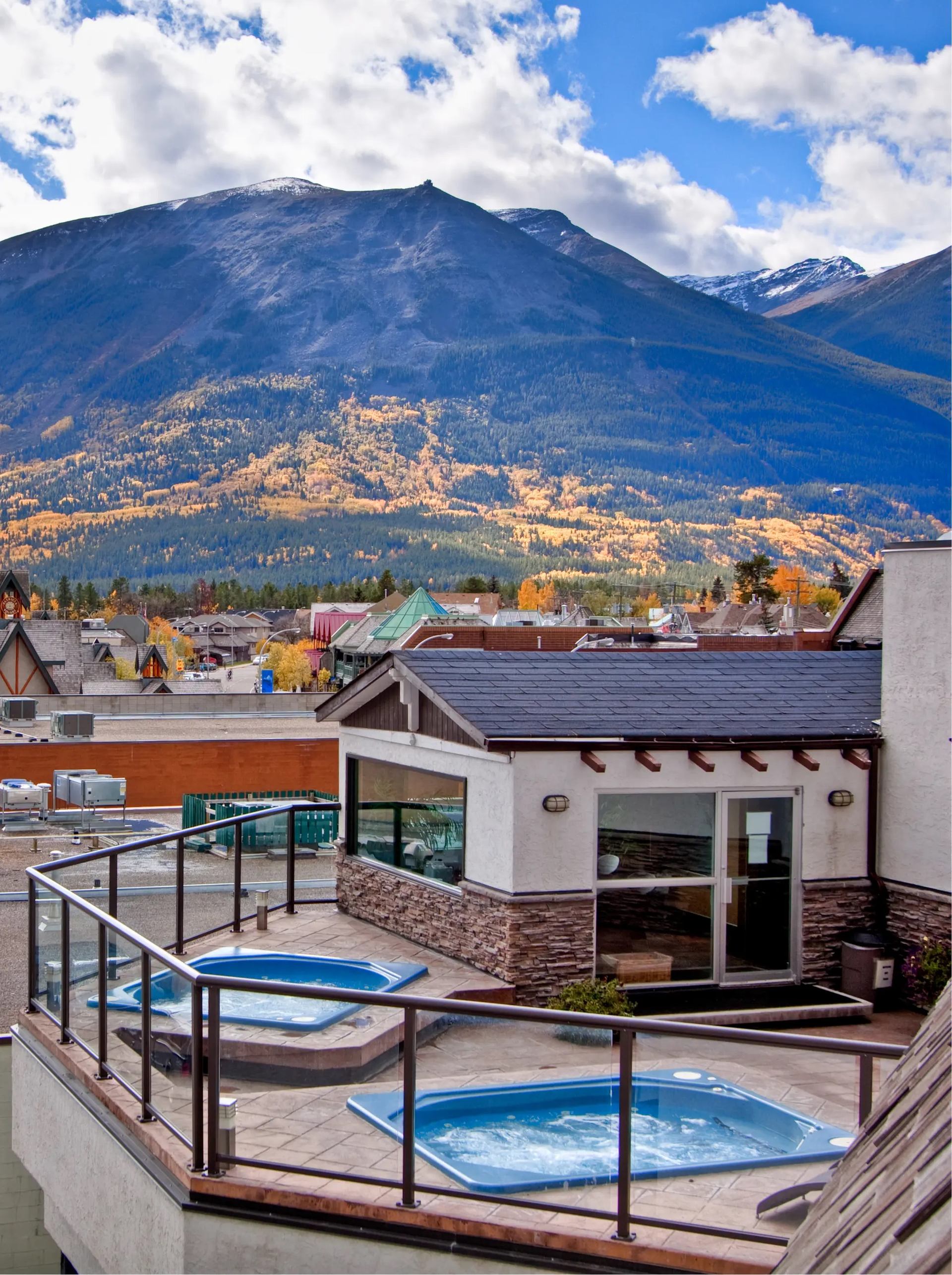 Rooftop hot tubs with mountain views, glass railings, and autumn foliage.