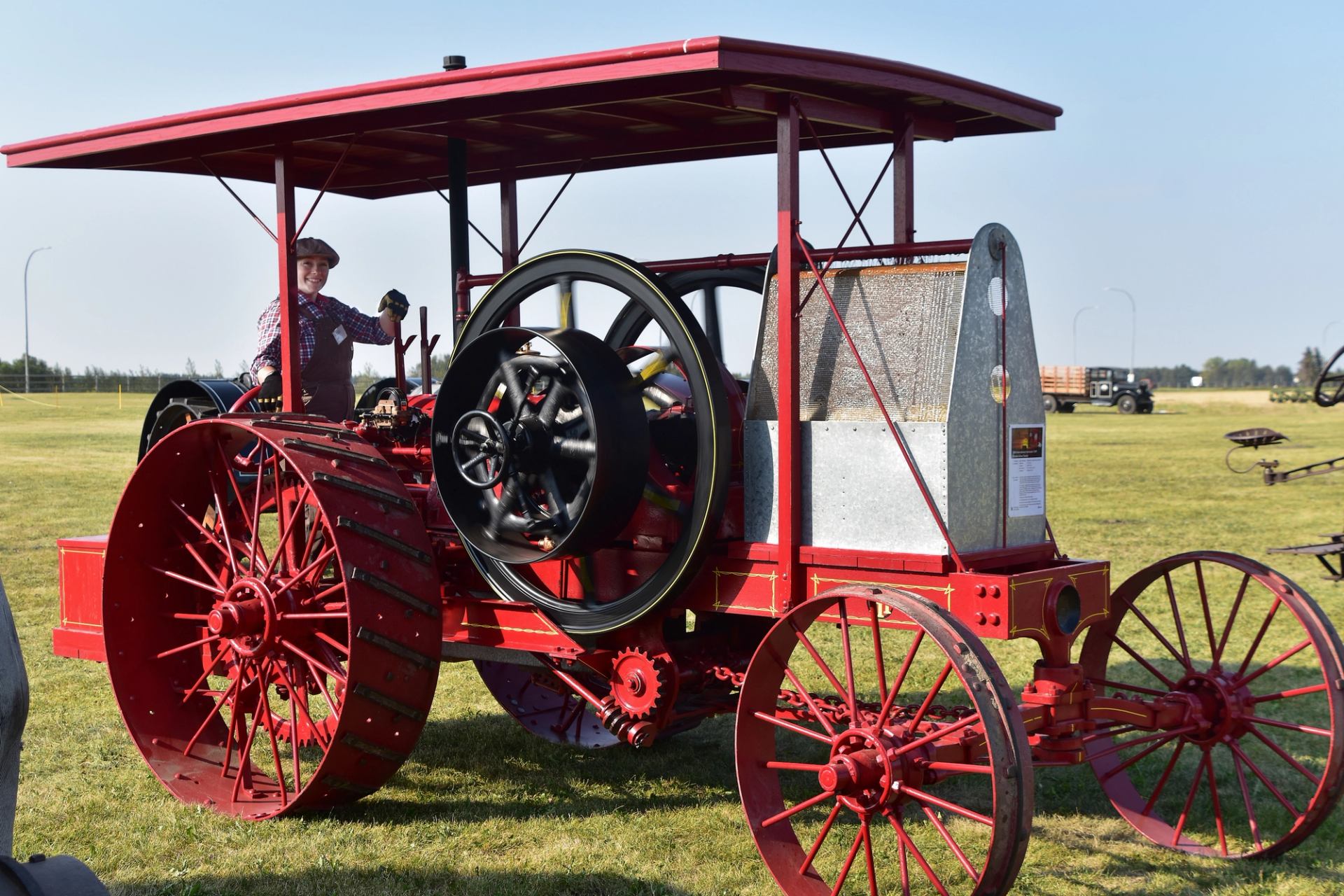Red antique tractor showcased on a sunny grassy field.