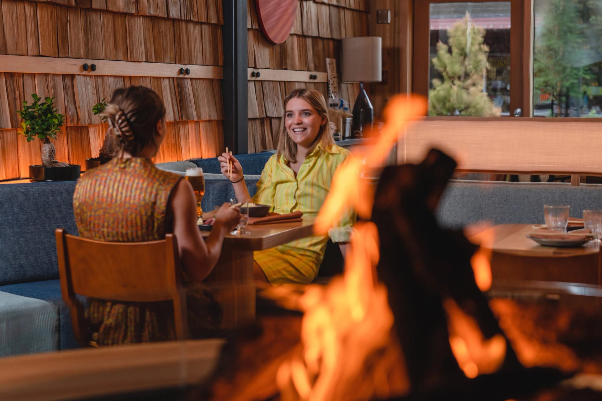 Two people dining in a cozy restaurant setting near a fire.