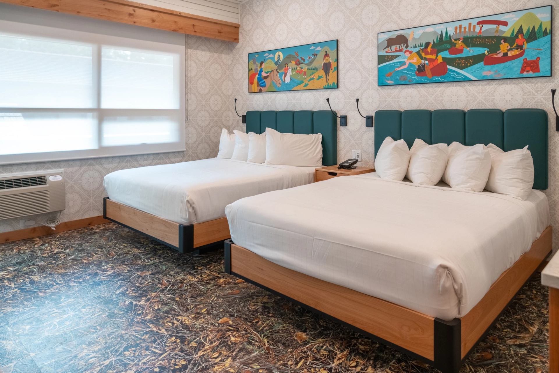 Double-bed room at The Dorothy Motel with teal headboards and vibrant artwork.
