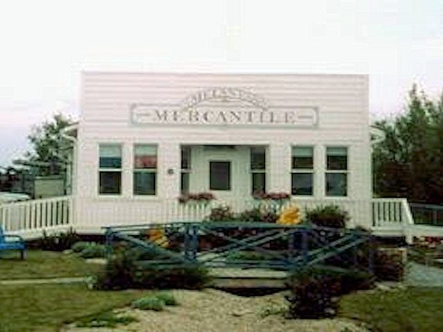 Historic white mercantile building with a porch and garden in front.