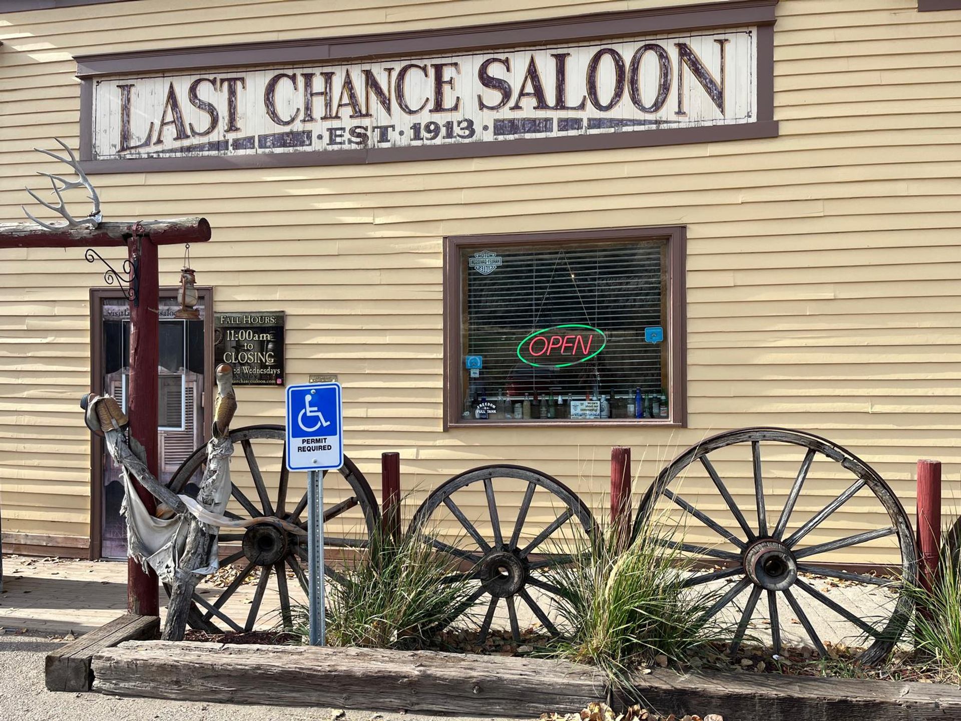 Historic saloon storefront features wooden wagon wheels, rustic décor, and an open sign