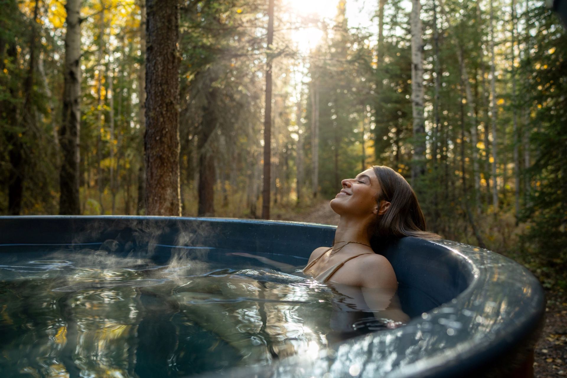 A woman smiles as she sits in an outdoor hot tub.