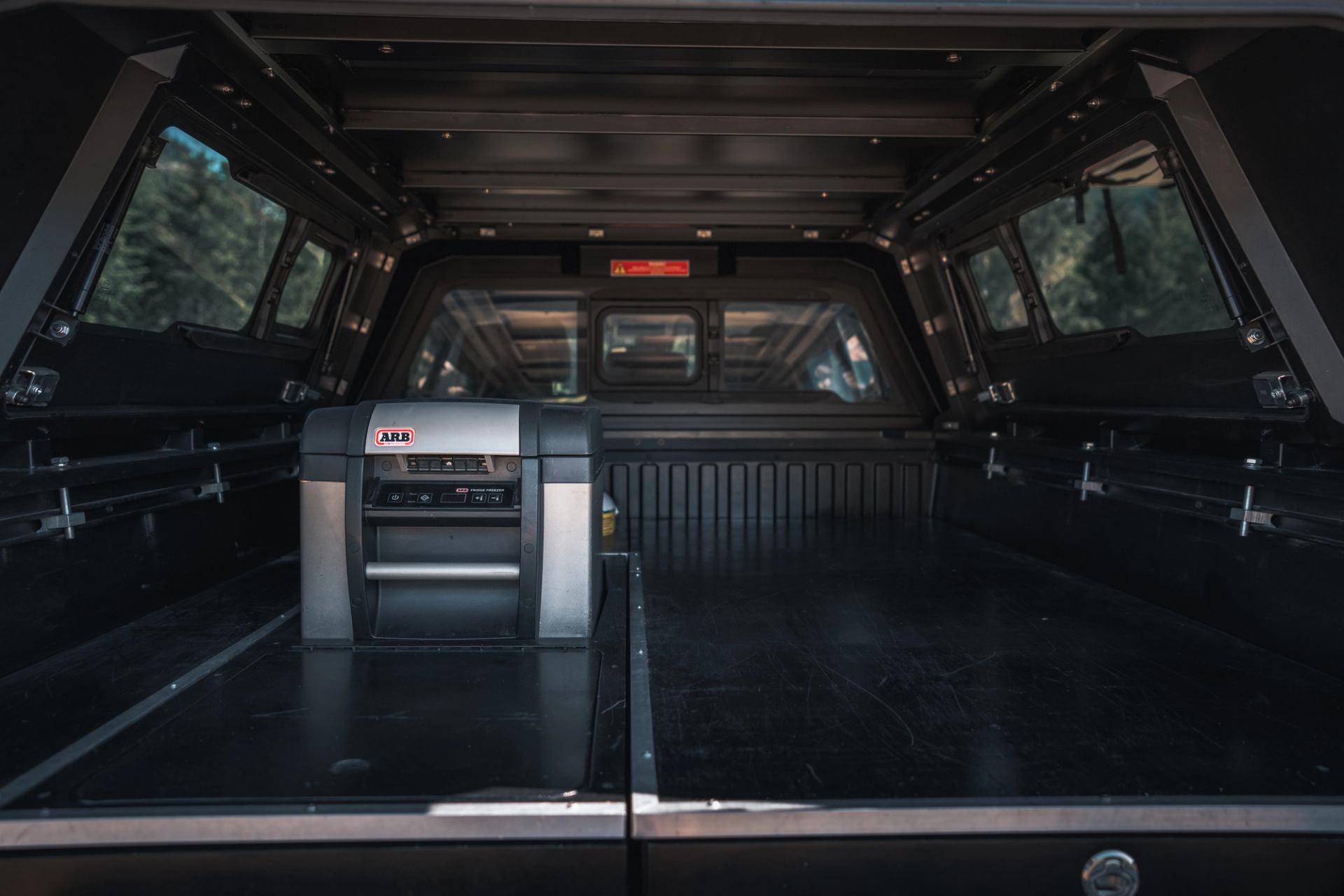 Interior of a truck bed with organized storage system and gear setup for outdoor travel.