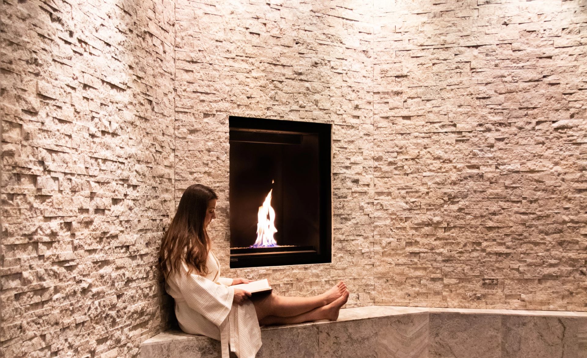A tranquil spa corner with a stone wall and built-in fireplace for relaxation.