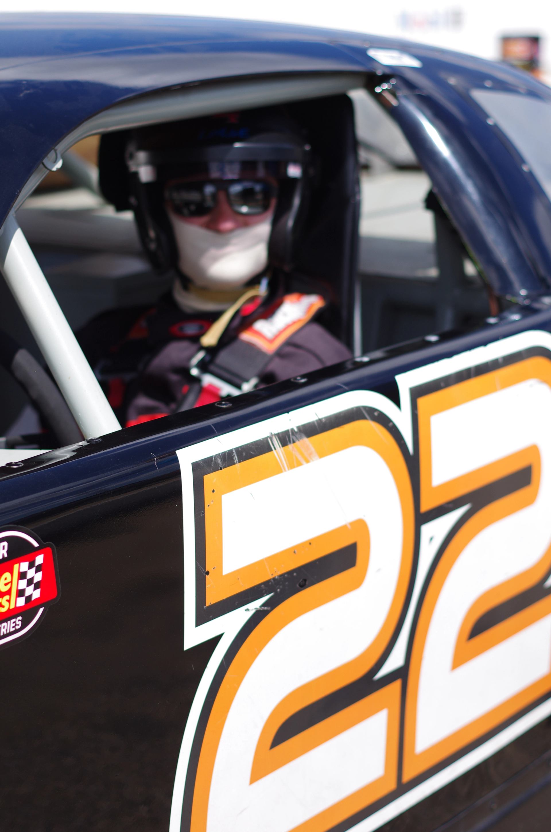 Driver seated inside a NASCAR stock car with number 22 on the door.